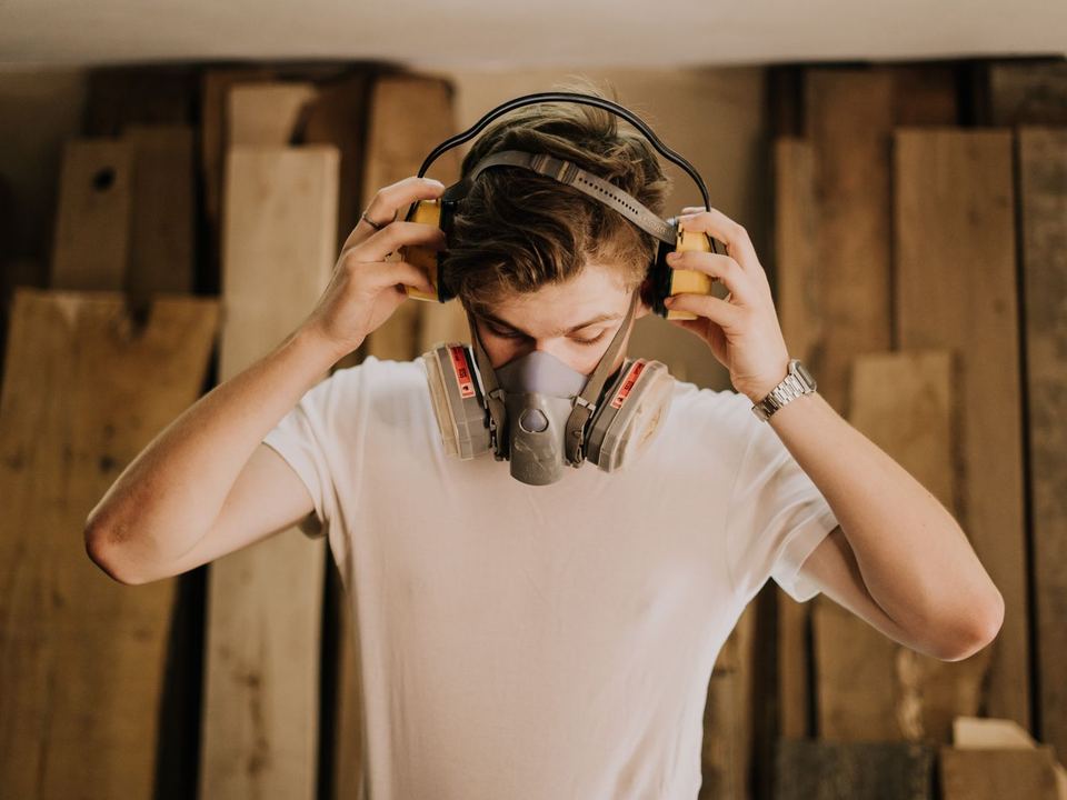 Woodworker putting on ear defenders and a dust mask