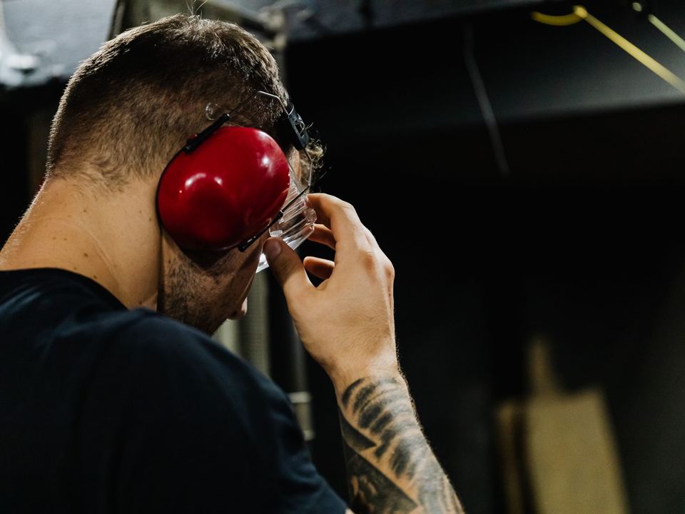 Worker adjusting red ear defenders and safety glasses